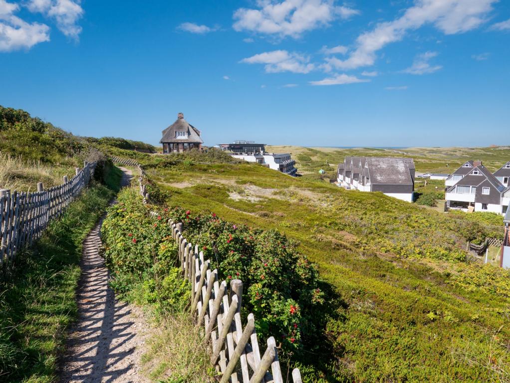 Weg durch die Dünen Sylts mit Blick auf Reetdachhäuser