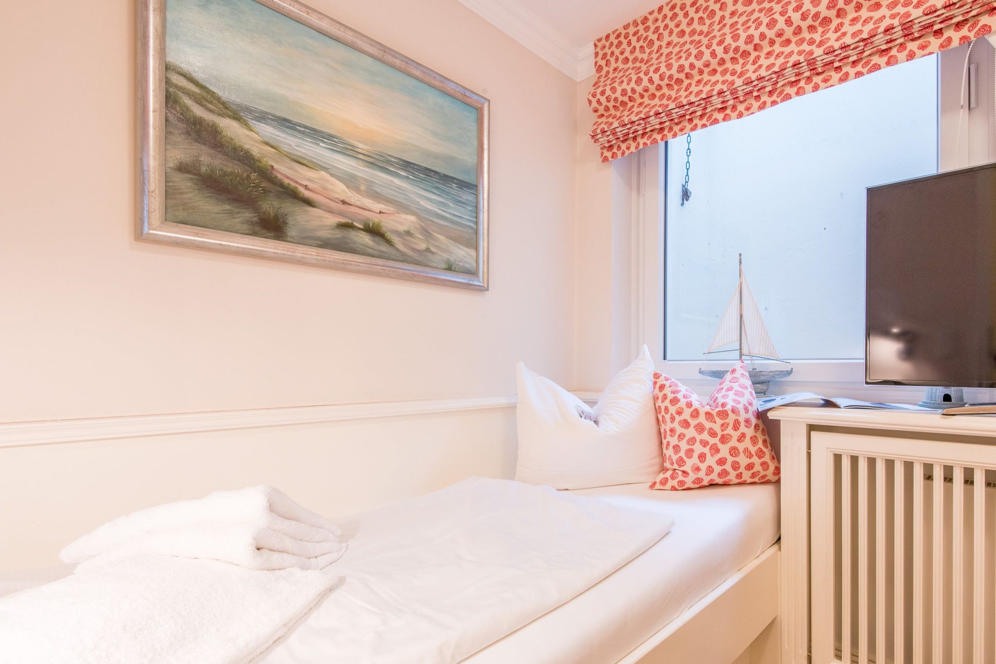 Schlafzimmer mit Einzelbett und Fernseher in Ferienhaus auf Sylt