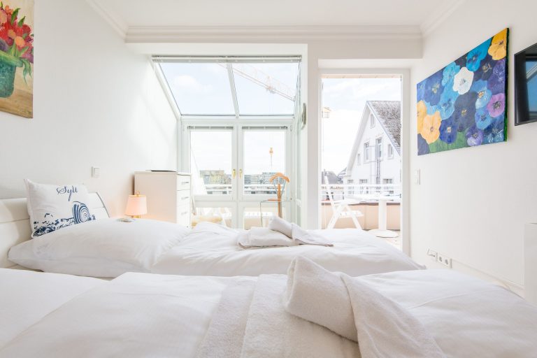 Doppelbett in Schlafzimmer und Balkon in Ferienhaus auf Sylt