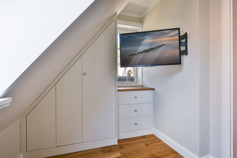 Schlafzimmer mit Schrank und Fernseher in Ferienhaus auf Sylt