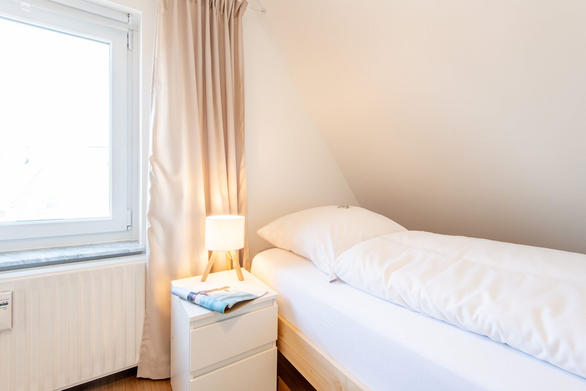Bett mit Nachttisch in einem Ferienhaus auf Sylt