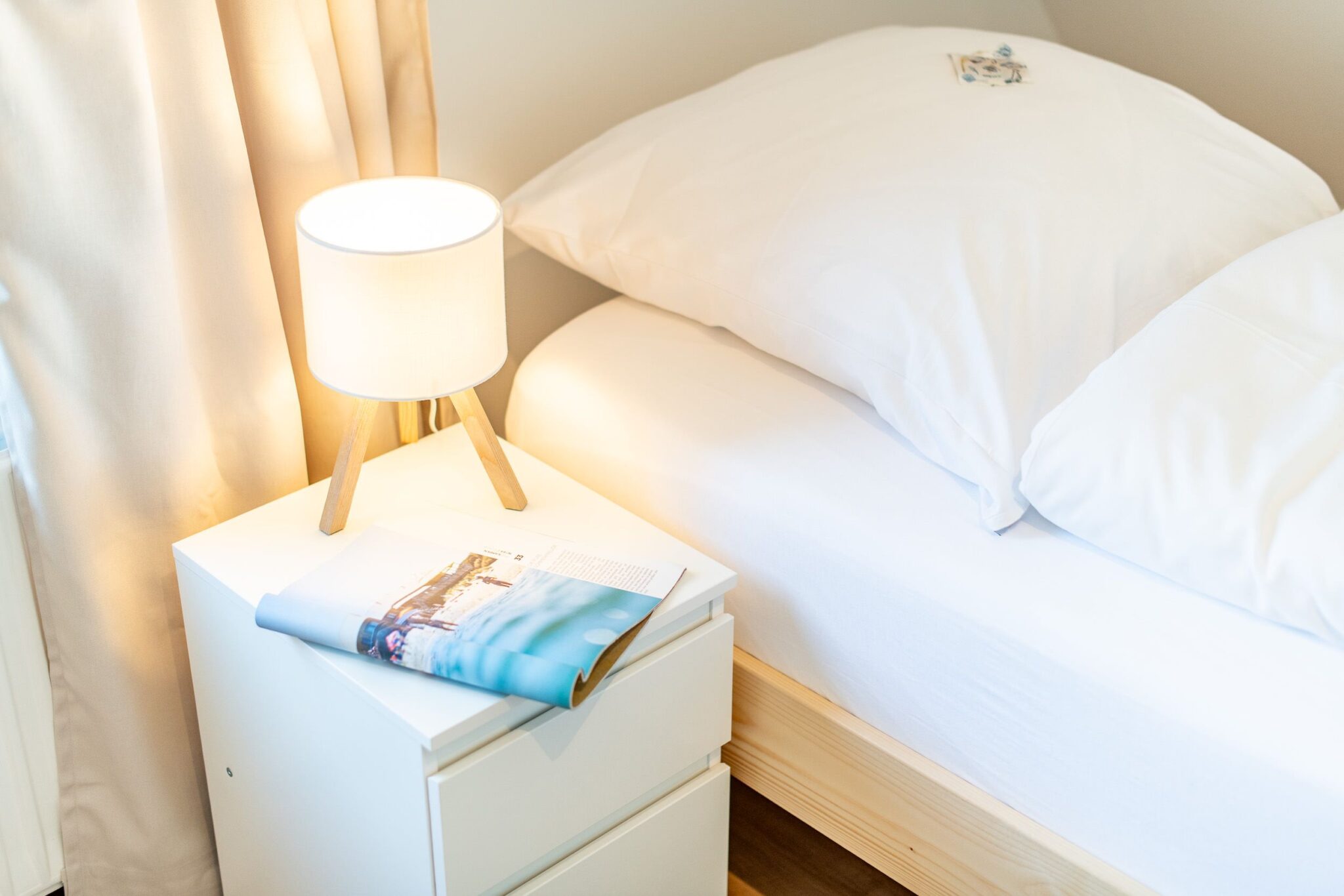 Nachttisch und Bett in einem Ferienhaus auf Sylt