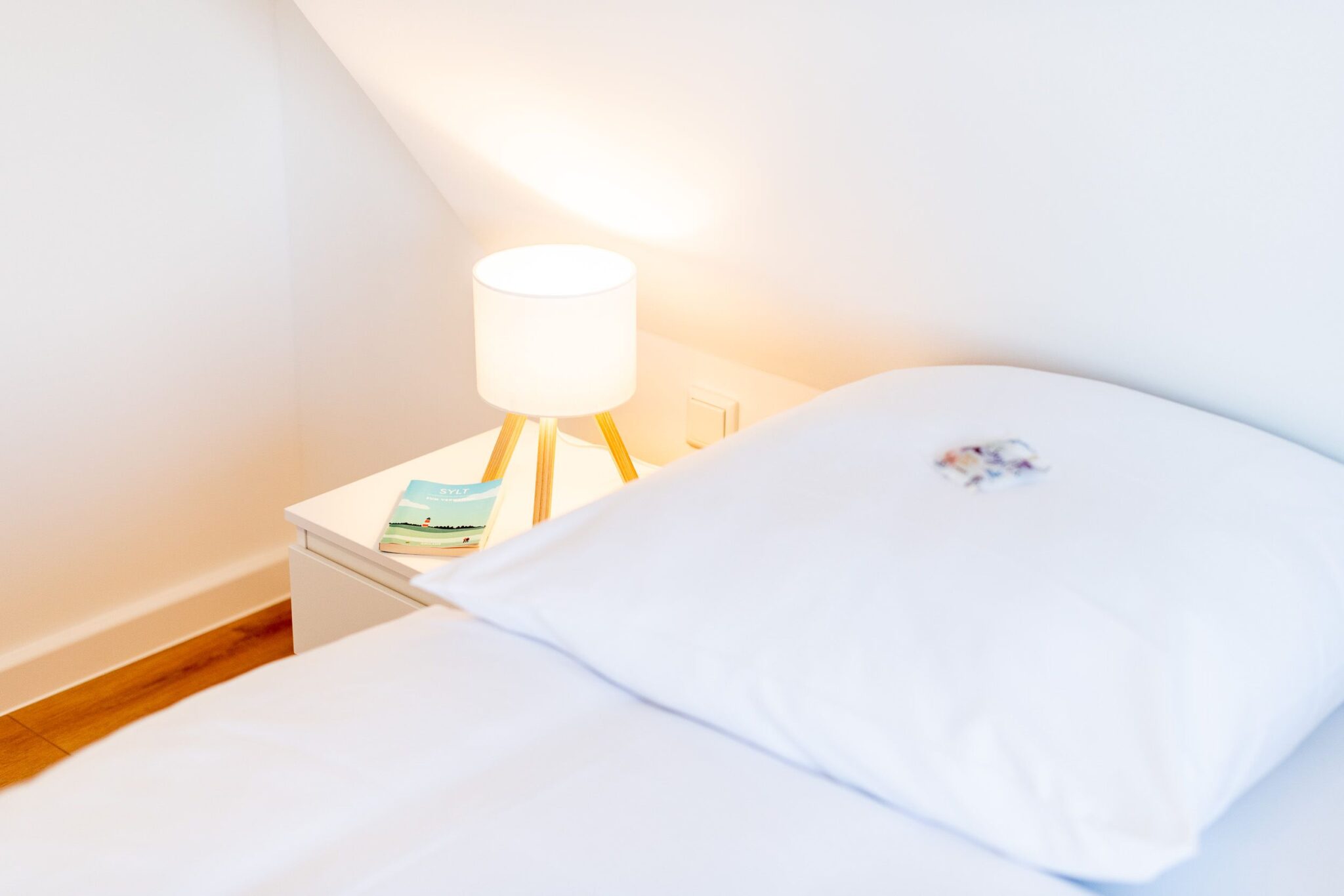 Bett mit Nachttisch in einem Ferienhaus auf Sylt