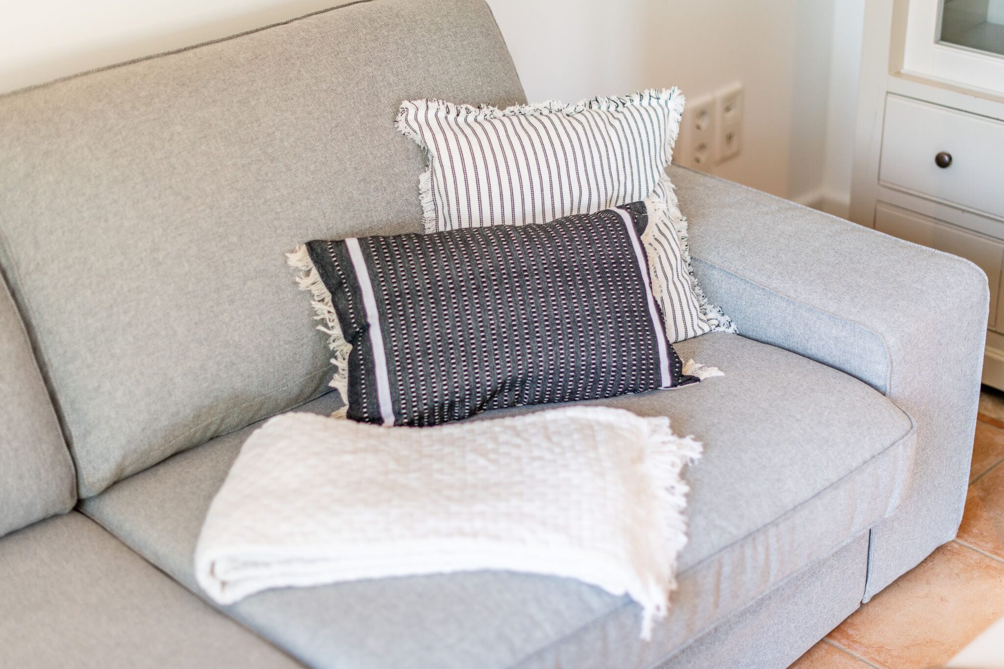 Kissen und eine Decke auf einem Sofa in einer Ferienwohnung auf Sylt