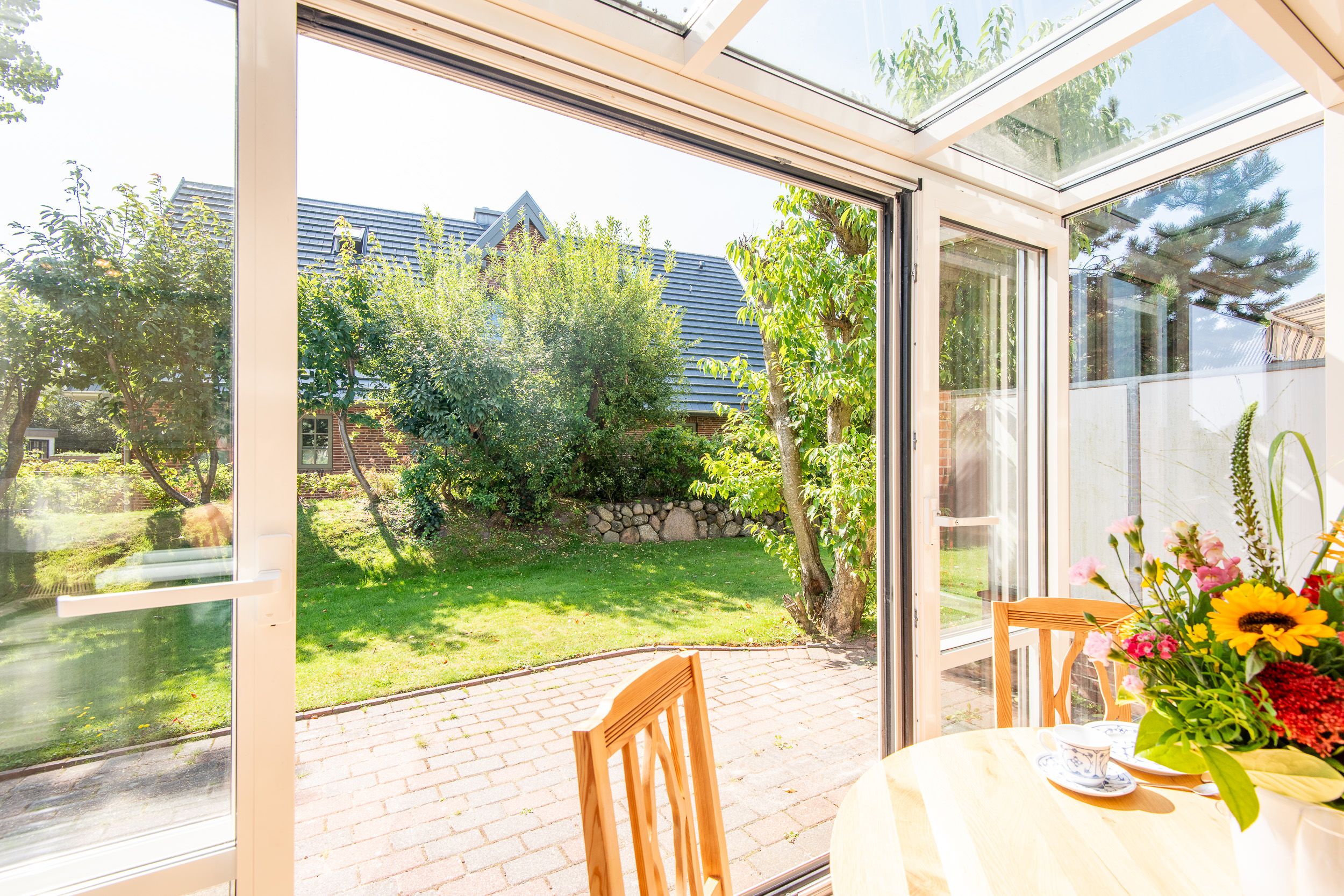 Blick in den Garten aus dem Wintergarten in einem Ferienhaus auf Sylt